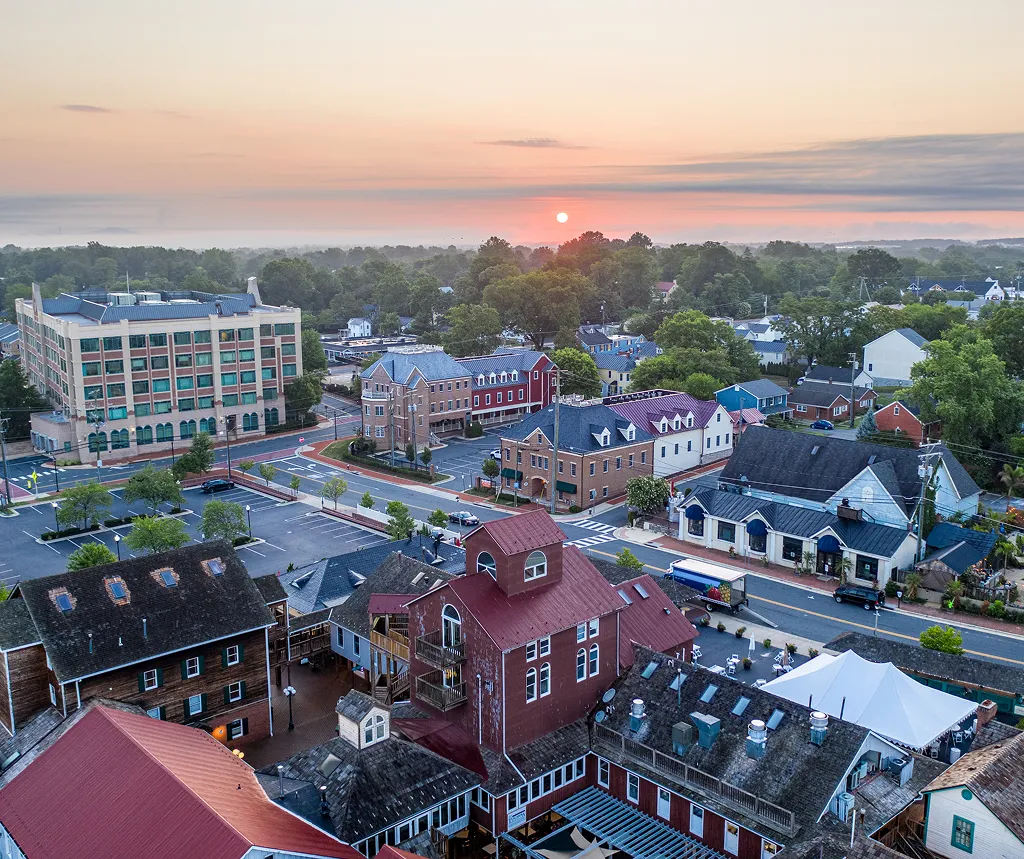 Aerial view of a small town at sunrise with mixed residential and commercial buildings.