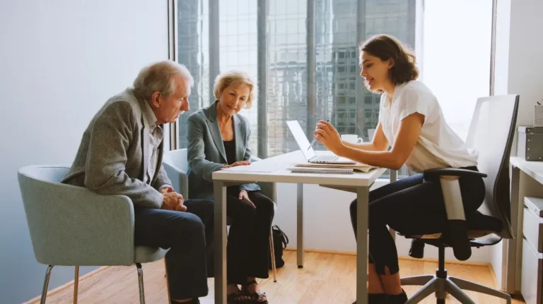 Three people engaged in a professional meeting in a modern office with large windows.