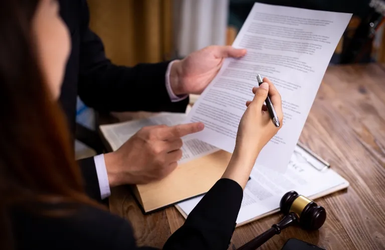 Two professionals reviewing a legal document at a wooden desk with a gavel and clipboard.